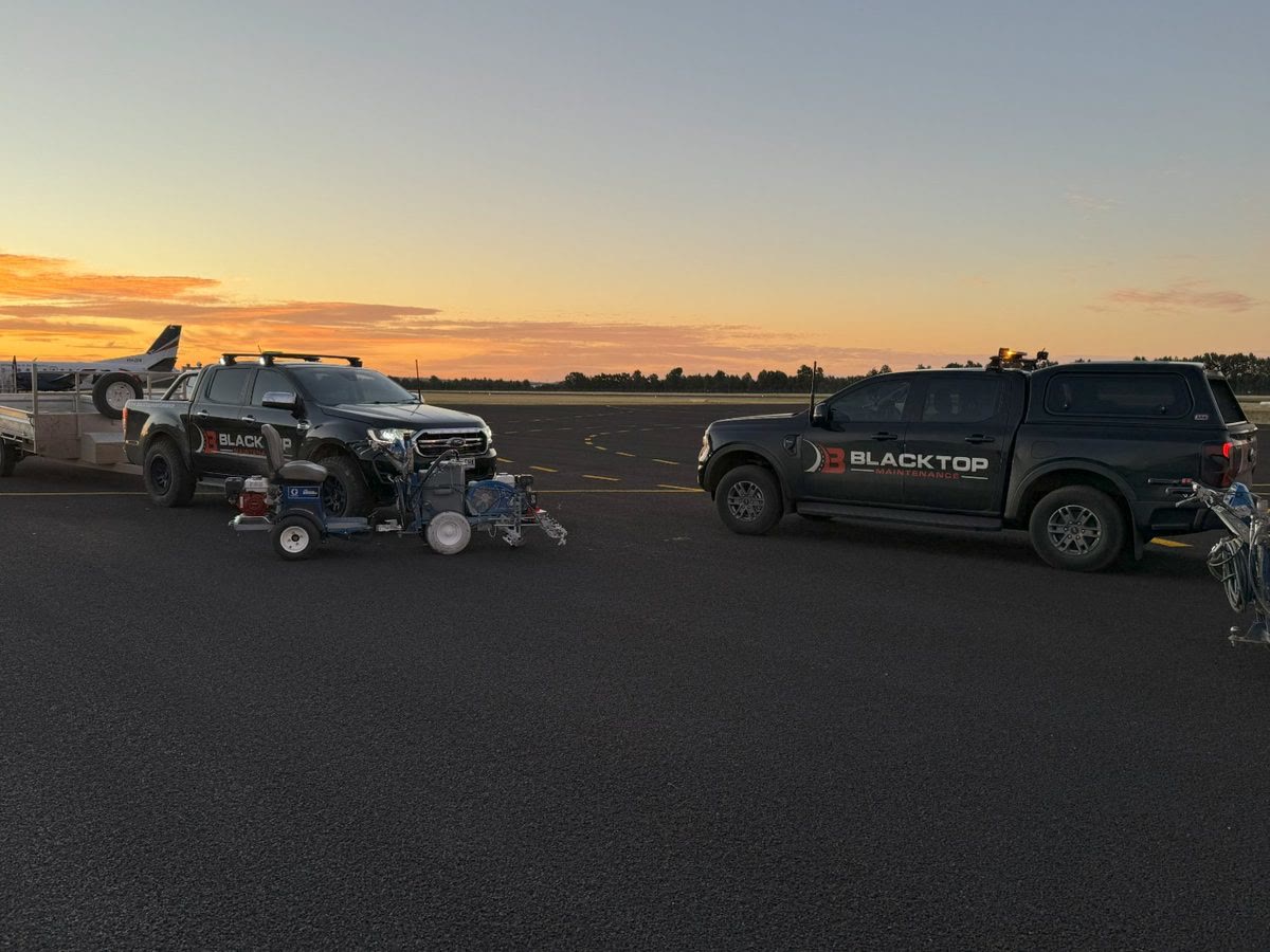 Blacktop Maintenance line marking utes and machines on an Adelaide airfield at sunset
