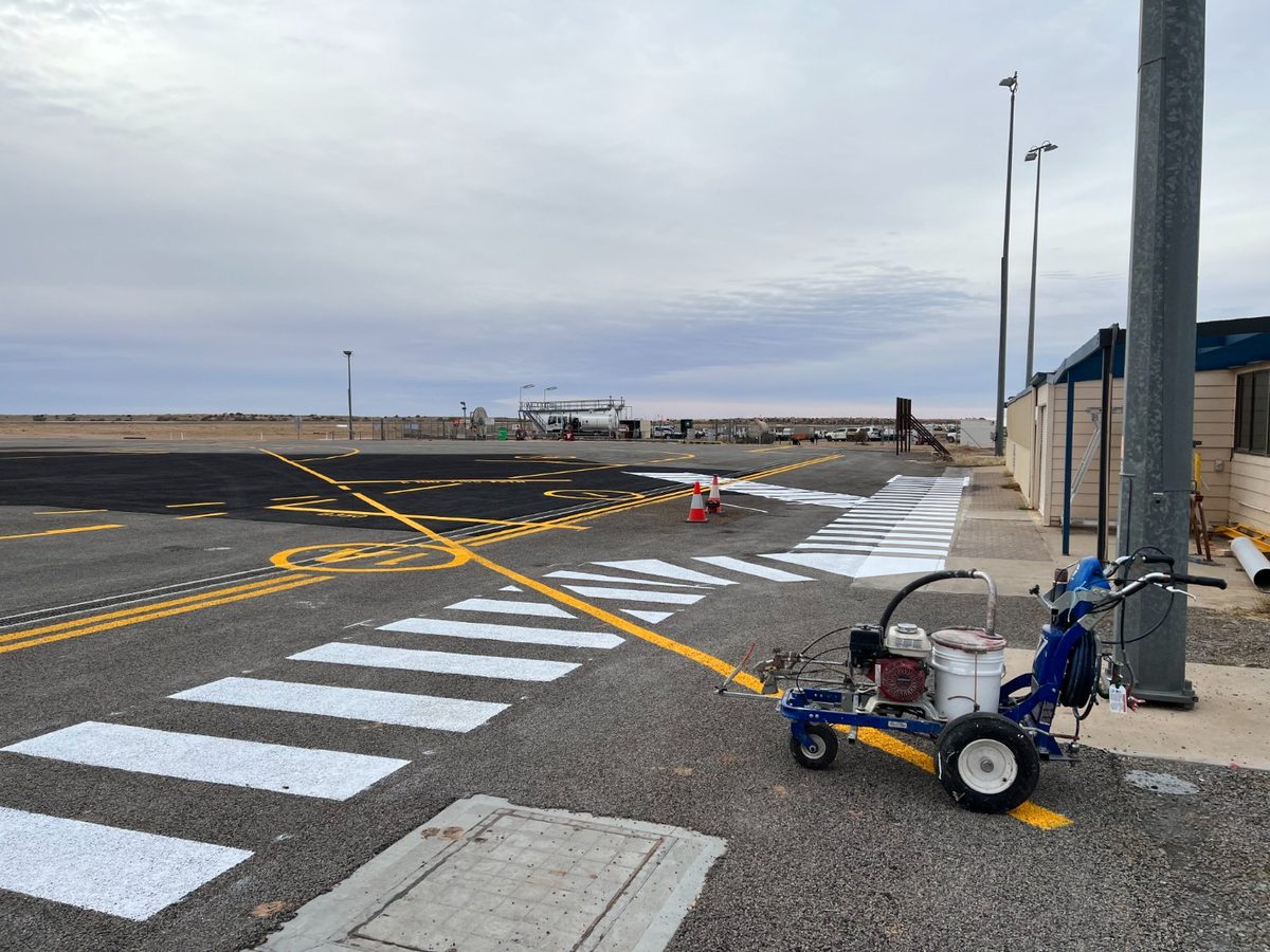 Crisp white line marking on a freshly sealed Adelaide apron beside a Blacktop line-marking machine